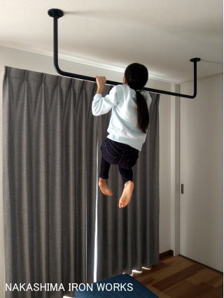 天井に取り付けた懸垂バーで懸垂をする女の子